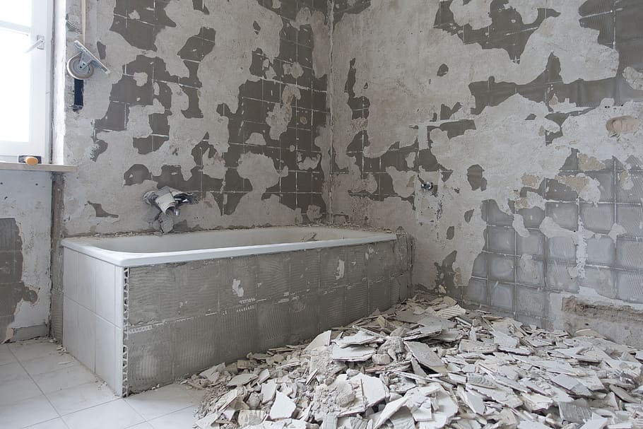 rectangular bathtub with demolished tile on the floor