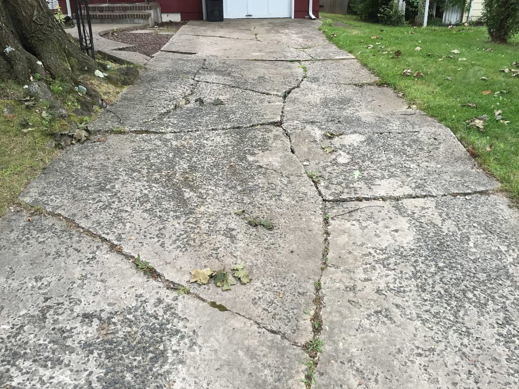 A severely cracked concrete driveway that requires replacement
