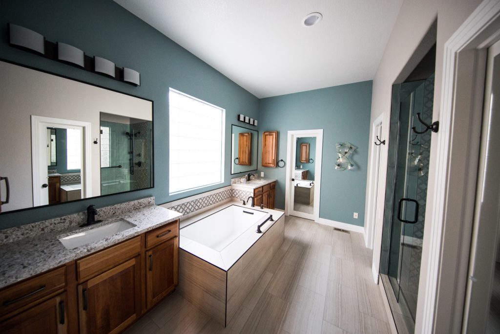 bathroom recently updated by Atlanta bathroom expert with blue walls, freestanding bathtub beneath a window, and granite counter