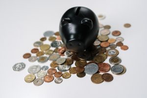 black piggy bank surrounded by coins