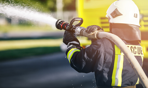 Firefighter in uniform and helmet spraying water