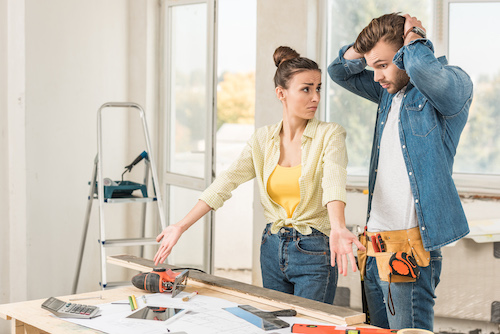 DIY couple annoyed while standing over home repair tools