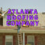 Atlanta roofing company written in purple over roofers repairing residential roof