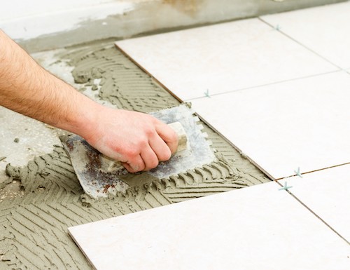 Bathroom floor tiling by manual worker.