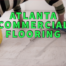 Atlanta commercial flooring written in green over worker laying grout between floor tiles