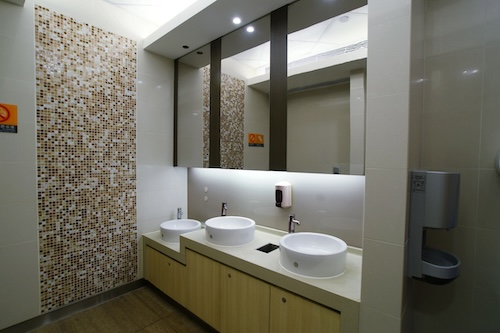 three sinks facing three mirrors inside a public bathroom